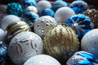 Yılbaşı baloları ve dekorasyonlar kapanıyor. Bir sürü altın, mavi, sarı, beyaz, gümüş madalya. Çizgili Noel topları yüzeyde yatıyor. Neşeli, güzel, renkli bir arka plan. Tasarım