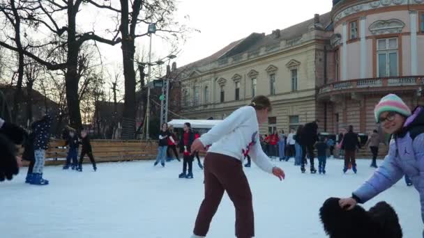 スレムスカ ミトロヴィツァ セルビア シティアイスケートリンク 子供と大人は楽しさと喜びで冬の日にスケートを楽しんでいます スクール休憩 クリスマス新年の祝日 犬の頭を傷つける少女 — ストック動画