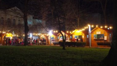 Sırbistan 'ın Sremska Mitrovica kenti, 12.28.2023: Kışın Central City Park' ta Noel pazarı. Sırp Yeni Yıl Fuarı 'nın dekorasyonları ve çarşıda el sanatları ile tezgahlar. İnsanlar yürür ve alışveriş yapar.