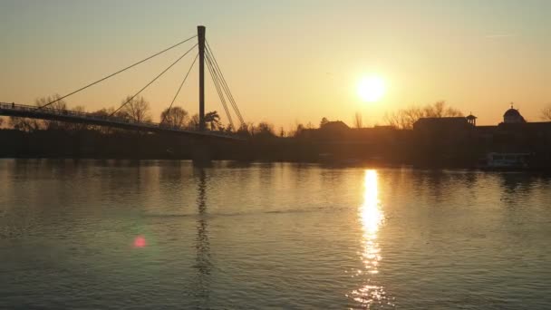 Sremska Mitrovica 塞尔维亚 Macvanska Mitrovica Sava河全景 圣Irineja的行人过桥 堤岸和城市建筑 黄日落日 有太阳盘 — 图库视频影像