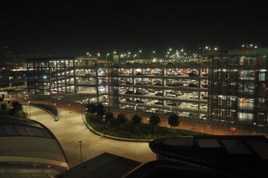 İstanbul, Türkiye, 31 Aralık 2023: IST havaalanı alanında arabalı çok katlı modern otopark. Bir Türk metropolünün altyapısı. Paralı otopark ve garaj. Binayı elektrik aydınlatıyor.