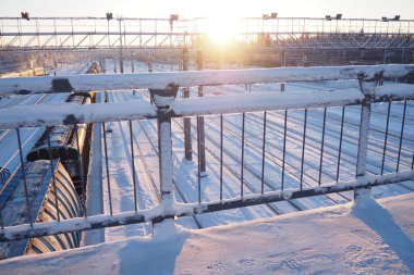 Tren istasyonunda. Yolcu yük trenleri raylarda. Kış kısa kutup günü. Kar ve kar yığınları.