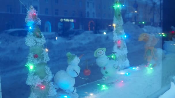 戏剧化的展示与一个可爱的冬季新年玩具雪人和娃娃在雪橇上 闪烁着圣诞佳节的花环 汽车前灯的闪光反映在玻璃上 圣诞装饰品有趣的玩具 — 图库视频影像