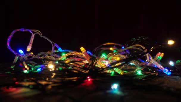 在地面上闪烁着彩色模糊的花环灯 新年背景 圣诞节 在黑暗中漂浮的焦点 节庆室照明和设计 红色绿色蓝色黄色灯泡 — 图库视频影像