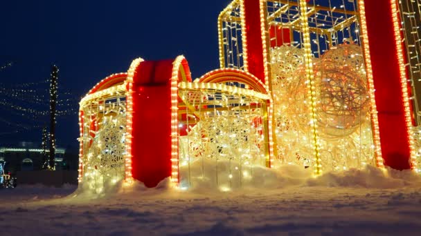 建筑形式为明亮的礼品盒 有巨大的蝴蝶结 由金黄色的红色花环做成 城市街道和广场的节日装饰 圣诞节和新年 圣诞之夜 — 图库视频影像
