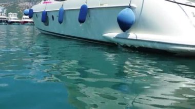 Yatın dibindeki sudan parlıyor. Dalgalar dalgalanır. Karadağ, Budva. Tekne yatı demir attı. Otoparka demirlenmiş gemiler. Adriyatik Denizi Akdeniz. Deniz yaz seyahati iş ve spor