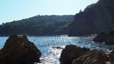 Mogren Sahili, Budva, Karadağ, yazın 8.15.22 plaj tatili. Mutlu turistler dinlenir, güneşlenir, deniz dalgalarında yüzer. Akdeniz 'in Adriyatik sahillerinde eğlence. Kumsal cenneti.