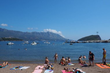 Budva, Karadağ 8.15.22 Çakıl taşı beton plajı Adriyatik denizi Akdeniz. Plaj şemsiyeleri ve havlular. İnsanlar rahatlar, yüzer, güneşlenir. Turizm sektörü. Yaz tatilindeki kadınlar ve erkekler.