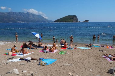 Budva, Karadağ 8.15.22 Çakıl taşı beton plajı Adriyatik denizi Akdeniz. Plaj şemsiyeleri ve havlular. İnsanlar rahatlar, yüzer, güneşlenir. Turizm sektörü. Yaz tatilindeki kadınlar ve erkekler.