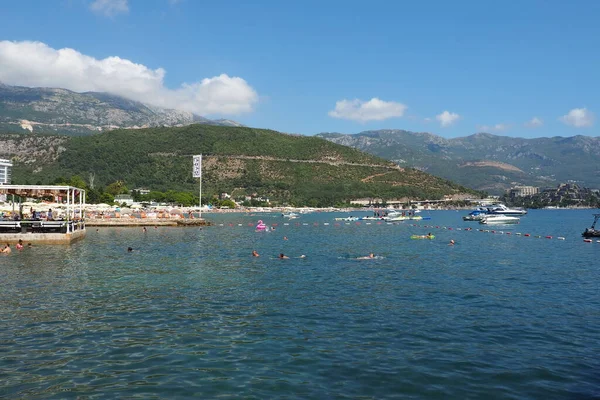 Budva, Karadağ 08.15.22 Pebble plajı. Plaj şemsiyeleri, kafeler, şezlonglar. İnsanlar rahatlar, yüzer, güneşlenir. Turizm sektörü Balkanlar. Halk plajı. Otel ve apartmanlar