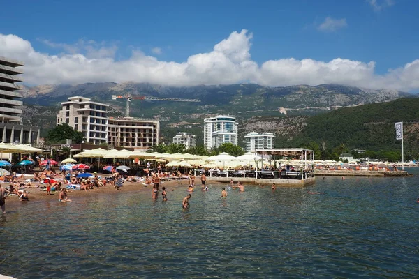 Budva, Karadağ 08.15.22 Pebble plajı. Plaj şemsiyeleri, kafeler, şezlonglar. İnsanlar rahatlar, yüzer, güneşlenir. Turizm sektörü Balkanlar. Halk plajı. Otel ve apartmanlar