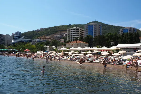 Budva, Karadağ 08.15.22 Pebble plajı. Plaj şemsiyeleri, kafeler, şezlonglar. İnsanlar rahatlar, yüzer, güneşlenir. Turizm sektörü Balkanlar. Halk plajı. Otel ve apartmanlar