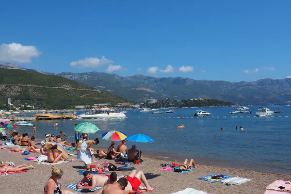 Budva, Karadağ 8.15.22 Çakıl taşı beton plajı Adriyatik denizi Akdeniz. Plaj şemsiyeleri ve havlular. İnsanlar rahatlar, yüzer, güneşlenir. Turizm sektörü. Yaz tatilindeki kadınlar ve erkekler.