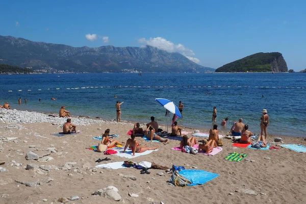 Budva, Karadağ 8.15.22 Çakıl taşı beton plajı Adriyatik denizi Akdeniz. Plaj şemsiyeleri ve havlular. İnsanlar rahatlar, yüzer, güneşlenir. Turizm sektörü. Yaz tatilindeki kadınlar ve erkekler.