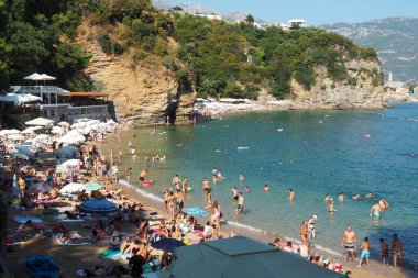 Mogren Sahili, Budva, Karadağ, yazın 8.15.22 plaj tatili. Mutlu turistler dinlenir, güneşlenir, deniz dalgalarında yüzer. Akdeniz 'in Adriyatik sahillerinde eğlence. Kumsal cenneti.