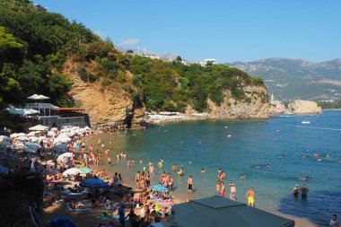 Mogren Sahili, Budva, Karadağ, yazın 8.15.22 plaj tatili. Mutlu turistler dinlenir, güneşlenir, deniz dalgalarında yüzer. Akdeniz 'in Adriyatik sahillerinde eğlence. Kumsal cenneti.