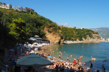 Mogren Sahili, Budva, Karadağ, yazın 8.15.22 plaj tatili. Mutlu turistler dinlenir, güneşlenir, deniz dalgalarında yüzer. Akdeniz 'in Adriyatik sahillerinde eğlence. Kumsal cenneti.