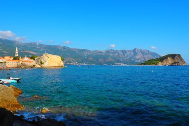 Budva, Karadağ 8.15.22 Adriyatik Denizi üzerinde güzel bir yaz günü. Sveti Nikola adası eski Budva kasabasının karşısında yer almaktadır. 121 metre yükselen bir uçurum. Turistler yüzüyor. Tekneler dalgalar üzerinde yelken açar