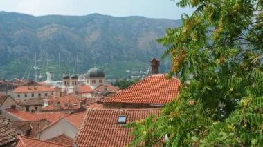 Kotor Karadağ 'da bir kıyı kentidir. Kotor Körfezi. Kırmızı kiremitli çatılar, dağ ve bir turist gemisinin bacaları. Geziler ve turizm. Aziz Tryphon Katedrali. Adriyatik 'teki ortaçağ eski kasabaları