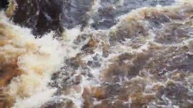 Nehirde akan su, üst manzara. Koyu demir su dereye hücum eder. Sarı-beyaz köpük. Karelia, Lososinka Nehri baharda, Onega Gölü 'ne dökülüyor. Seller, tsunami ve iklim değişikliği.