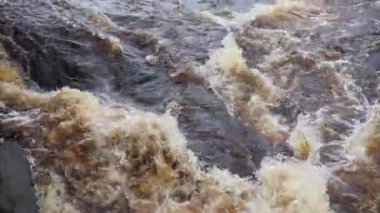 Nehirde akan su, üst manzara. Koyu demir su dereye hücum eder. Sarı-beyaz köpük. Karelia, Lososinka Nehri baharda, Onega Gölü 'ne dökülüyor. Seller, tsunami ve iklim değişikliği.