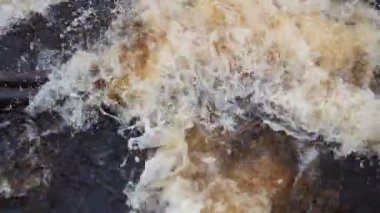 Nehirde akan su. Nehirde su akıyor. Nehir metal borulardan akar. Sarı-beyaz köpük. Karelia, Lososinka Nehri baharda. Seller, tsunami ve iklim değişikliği.