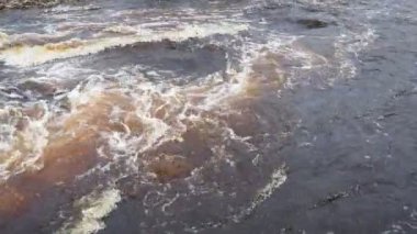 Bahar baskını. Nehirde akan su, üst manzara. Koyu demir su dereye hücum eder. Sarı-beyaz köpük. Karelia, Lososinka Nehri baharda. Seller, tsunami ve iklim değişikliği. Su hareketi