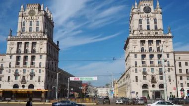 Minsk, Belarus, 10 Nisan 2024 tren istasyonunun önündeki istasyon meydanı. Arabalar, kamyonlar ve otobüsler geçiyor. İnsanlar yürüyor. Güneşli bir bahar günü. Görkemli kule binaları ve Kirov Bulvarı.