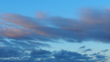 A cloud is product of water vapor condensation suspended in the atmosphere and visible in the sky. Accumulation of individual water particles. Evening sunset, blue and pink reflections. Real time.