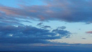 A cloud is product of water vapor condensation suspended in the atmosphere and visible in the sky. Accumulation of individual water particles. Evening sunset, blue and pink reflections. Real time.