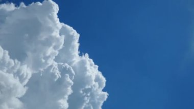 Güneşli mavi gökyüzünde güzel beyaz bulutlar. Ses ötesi ışık efekti. Troposferde korunma. Zaman atlaması hareketi. Kümülüs bulutları düşük seviye, kabarık, pamuk gibi, tüylü Cumulonimbus
