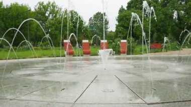 Varşova, Polonya, Park Pieciu Siostr, Warszawa, 04.09.24: Fontanna Ochocka Patelnia. Zahodnij Parkı. Beklenmedik çok yönlü su sıçramaları olan bir çeşme. Bahar günü. Yoldan geçenler geçiyor.