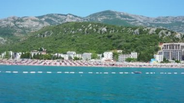 Canj Montenegro 07.21.24 Tatilciler, güneşlenenler ve yüzücülerle dolu bir tekne turu. Oteller, güneş şemsiyeleri, Adriyatik dalgaları, şamandıralar. Plaj turizmi. Tatil seyahati. Yaz günü. Kumlu çakıl taşı plajı.