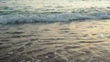 Dalgalar sersemletici günbatımında yavaşça kıyıya vurur. Altın güneş ışığı, dalgaların kıyıya vuruşunu yansıtır. Gün batımında deniz kenarında sakin bir atmosfer yaratır. Karadağ yazı, Canj