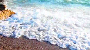 Dalgalar sersemletici günbatımında yavaşça kıyıya vurur. Altın güneş ışığı, dalgaların kıyıya vuruşunu yansıtır. Gün batımında deniz kenarında sakin bir atmosfer yaratır. Karadağ yazı, Canj