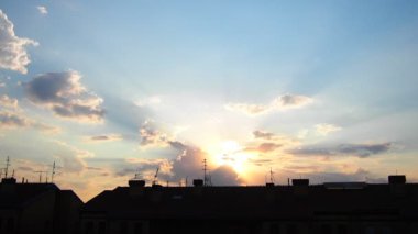 Sarı mavi günbatımı gökyüzü bulutları. Yumuşak, ılık sarı renkler huzurlu ve huzurlu bir atmosfer yaratıyor. Batan güneşin hafif ışınları altın dokunuşuyla ufku boyuyor. Şehrin çatısında gün batımı. Gerçek zamanlı..