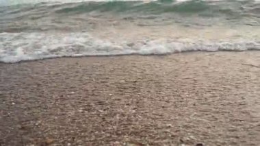 Dalgalar sersemletici günbatımında yavaşça kıyıya vurur. Altın güneş ışığı, dalgaların kıyıya vuruşunu yansıtır. Gün batımında deniz kenarında sakin bir atmosfer yaratır. Karadağ yazı, Canj.