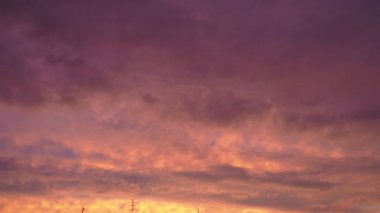 Sarı turuncu kırmızı günbatımı gökyüzü bulutları. Sarı ve kırmızının yumuşak ılık tonu dingin ve güzel bir atmosfer oluşturur. Batan güneşin yumuşak ışınları ufku boyuyor. Dramatik gün batımı. Gerçek zamanlı, kümülüs bulutları