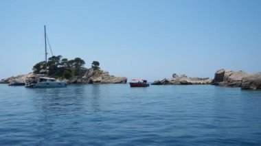Petrovac, Karadağ, 07.27.24: Katiç, Sveta Nedelja, Karadağ 'ın Budva belediyesinin Petrovac kentinin karşısındaki Adriyatik Denizi üzerinde yer alan iki küçük ada. Turistler, tekneler ve gemiler.