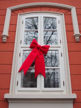 A charming window decorated for the New Year and Christmas showcases a large red bow, creating a joyful atmosphere for a winter festival or holiday gathering clipart