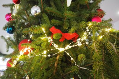 Parlak kırmızı ve gümüş toplarla süslenmiş canlı bir Noel ağacı, parlak çelenkler ve şenlikli kurdeleler, yeni yıl mevsiminde sıcacık bir ortamda bayram neşesi yayıyor. Neşeli kış havası.
