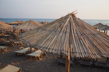 Karadağ 'ın Canj kenti: 07.20.2024 Güneş şezlongları ve saman şemsiyeleri, güneşli bir günde sakin sularda dinlenmek için sakin bir atmosfer yaratarak Bar Beach' te kıyı şeridi oluşturuyorlar. Adriyatik Akdeniz.