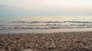 Alacakaranlık çöktüğünde kumlu bir plaja yumuşak dalgalar vuruyor. Sakin deniz, sönen ışığı yansıtır ve akşam dinlenmesi için sakin bir atmosfer yaratır. Pembe ışınların yansıması. Akdeniz Adriyatik Denizi.