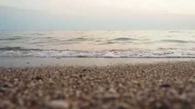 Alacakaranlık çöktüğünde kumlu bir plaja yumuşak dalgalar vuruyor. Sakin deniz, sönen ışığı yansıtır ve akşam dinlenmesi için sakin bir atmosfer yaratır. Işınların yansıması. Akdeniz Adriyatik Denizi.