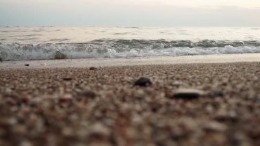 Alacakaranlık çöktüğünde kumlu bir plaja yumuşak dalgalar vuruyor. Sakin deniz, sönen ışığı yansıtır ve akşam rahatlığı için sakin bir atmosfer yaratır. Sarı ışınların yansıması. Akdeniz Adriyatik Denizi.