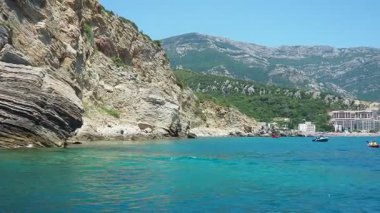 Canj, Karadağ 07.27.2024: Tatilciler, güneşlenenler ve yüzücülerin bulunduğu bir tekne turu. Oteller, güneş şemsiyeleri, Adriyatik dalgaları, şamandıralar. Plaj turizmi. Tatil seyahati. Yaz günü. Kumlu çakıl