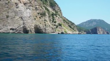 Pecina mağarası, plaj Miina Plaza, Bar Montenegro. Tepeler, ulaşılamaz kayalar. Sinek, deniz tortulu kayalar, litolojik katmanlar. Adriyatik Akdeniz. Denizde tekne gezisi. Yaz deniz turizmi.