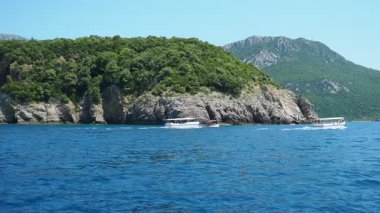 Kralicna plaza King plajı, Canj, Bar, Karadağ 07.22.24 Tatilciler, güneşlenenler, yüzücüler. Adriyatik Akdeniz. Zevkli tekneler turist taşır. Kayalar ve taşlar arasında Akdeniz bitkisi