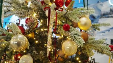 Altın ve kırmızı süslemelerle süslenmiş güzel bir Noel ağacı ılık ışıklarla hafifçe parlar. Festival dekorasyonları tatil sezonu için mükemmel bir ortam yaratıyor. Dönen Noel ağacı