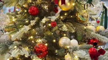 Altın ve kırmızı süslemelerle süslenmiş güzel bir Noel ağacı ılık ışıklarla hafifçe parlar. Festival dekorasyonları tatil sezonu için mükemmel bir ortam yaratıyor. Dönen Noel ağacı